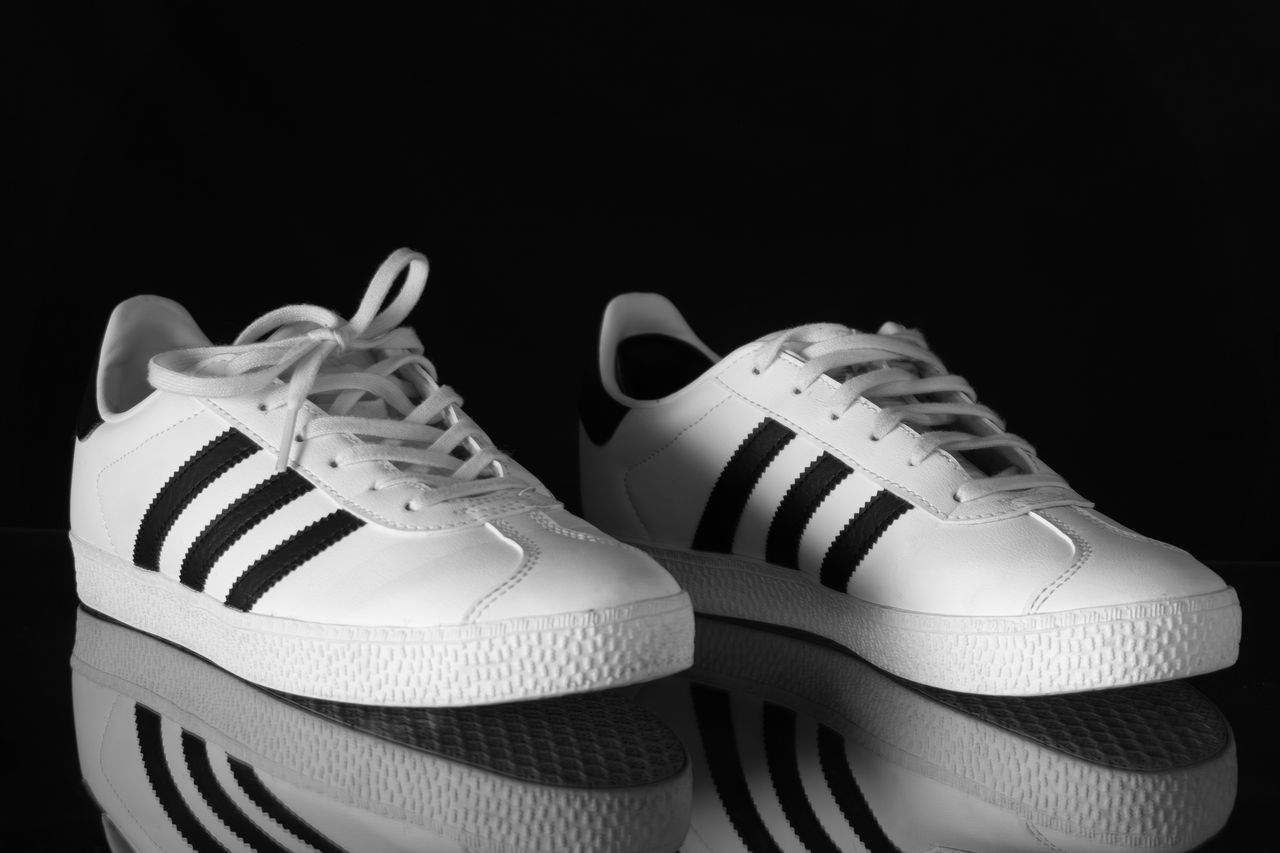 Mastering the First Impression: Your intriguing post title goes here Classic white sneakers with black stripes reflecting against a dark background.